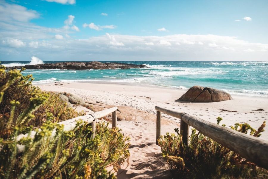 Sandstrand mit Holzgeländer und türkisfarbenem Meer